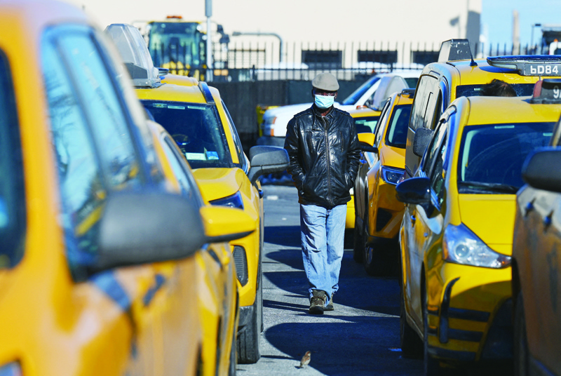 A yellow cab taxi driver walks between cars as he waits in line at a taxi hold at LaGuardia Airport in New York City. - AFPn