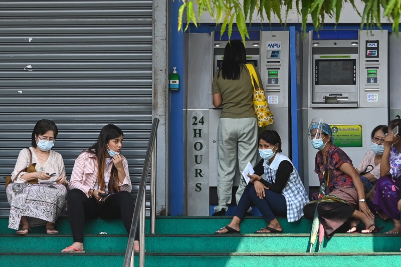 YANGON: People wait to withdraw money from a Myawaddy Bank automated teller machine (ATM) in Yangon on Tuesday.-AFPnn