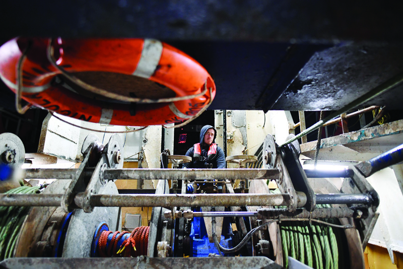 Plymouth fishing boat trawlerman and captain of the stern trawler 'Nicola Anne' Kyle Bishop Meades controls the winch as the net is released for the first trawl of the day, at sea off the south-west coast of England. - AFPn