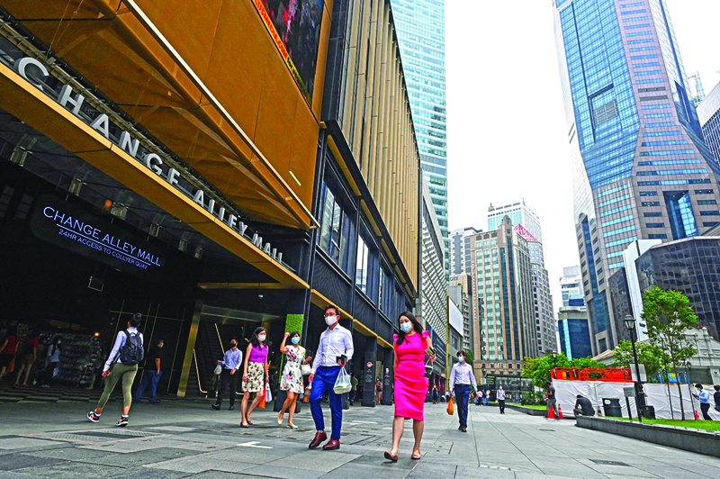 SINGAPORE: People walk during lunch time at the Raffles Place financial business district in Singapore yesterday.-AFPn