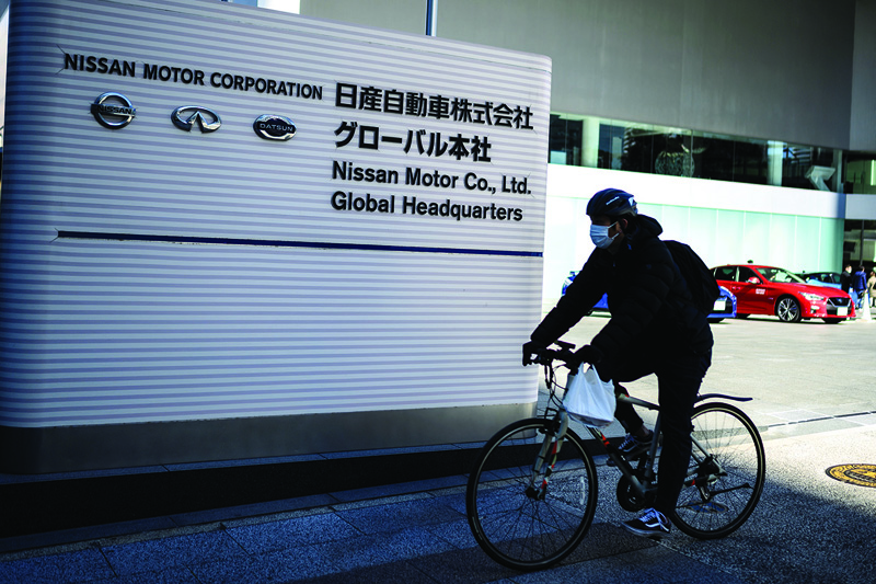 YOKOHAMA: A man rides his bicycle past signage at the Nissan Motor global headquarters in Yokohama, Kanagawa prefecture yesterday.-AFPn