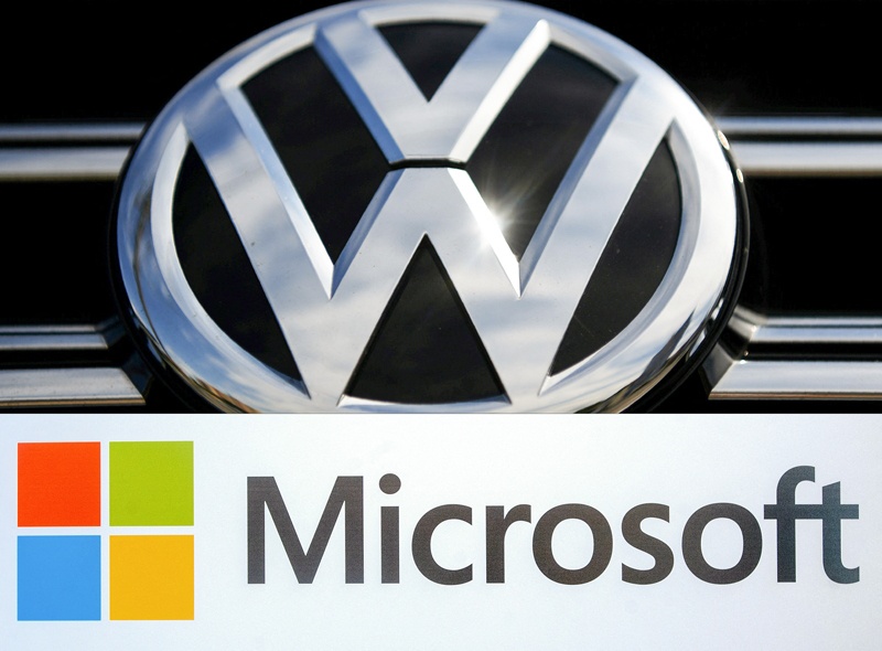  This combination of file pictures created on February 11, 2021 shows the Volkswagen logo on a car parked in the forecourt of an inner city Volkswagen dealership (in Sydney on March, 12, 2017) and the Microsoft logo before the start of a media event (in San Francisco, California on March 27, 2014). German auto giant Volkswagen and US tech leader Microsoft said on February 11, 2021 they were joining forces to develop autonomous vehicle driving systems, cementing a 2018 partnership to exploit the possibilities of the Cloud. Volkswagen said it aims to speed up development of such connected systems, which are increasingly becoming the norm in the auto industry as it transitions to electric vehicles.n