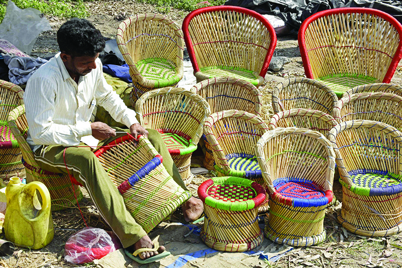 AMRITSAR: A craftsman makes chairs along the roadside yesterday. — AFP