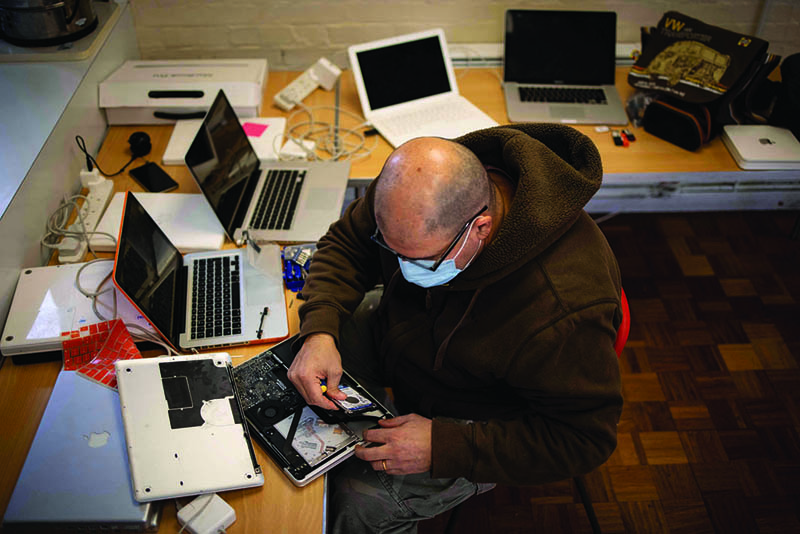 LONDON: A member of the team at Catbytes, a computer repair charity, repairs a donated computer at Ewart Community Hall in south London.-AFP n
