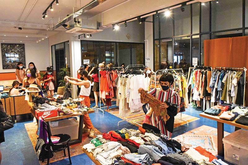 This picture shows shoppers browsing through secondhand clothes at a pop-up swap event organized by a group of volunteers in Singapore.-AFP photosn