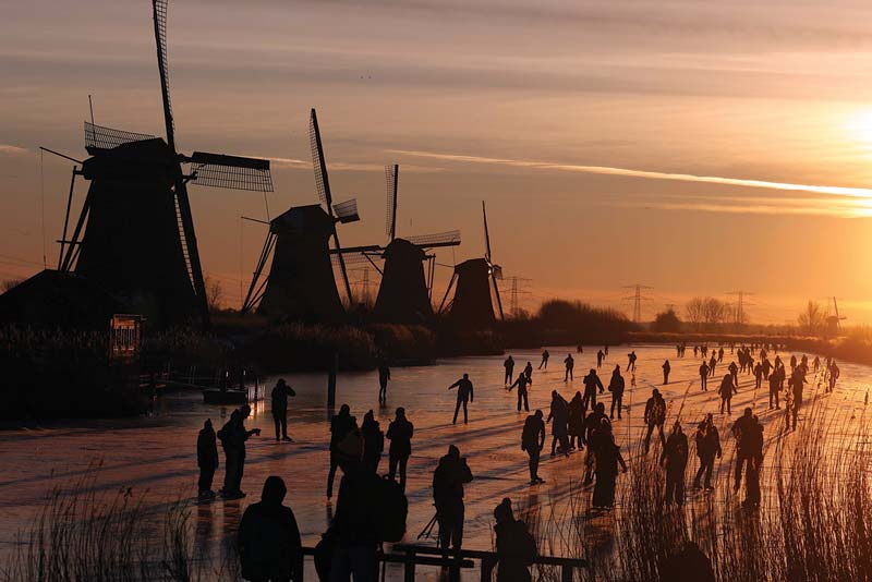 Skaters glide on the ice near windmills in the village of Kinderdijk.-AFP photosn