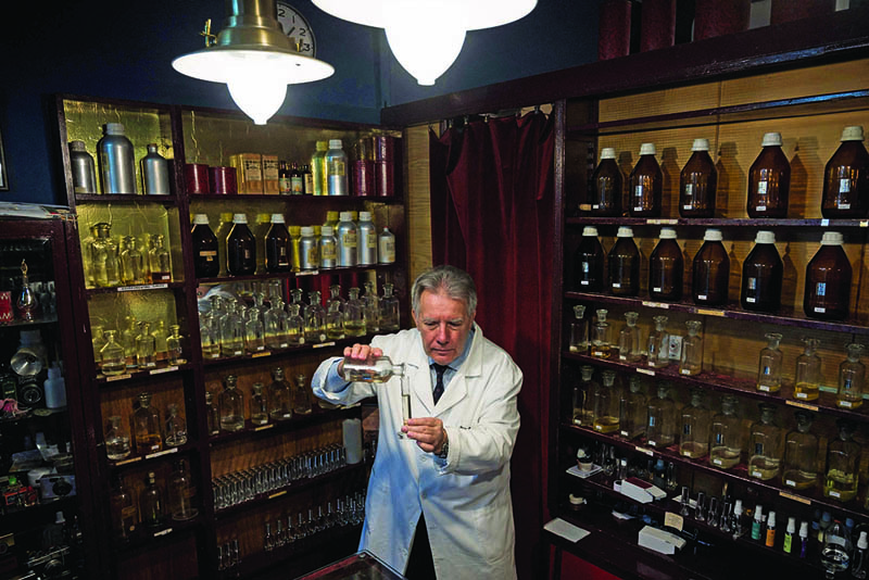 Nenad Jovanov poses for a picture with perfume bottles in his 67 years old perfume shop in Belgrade.-AFP