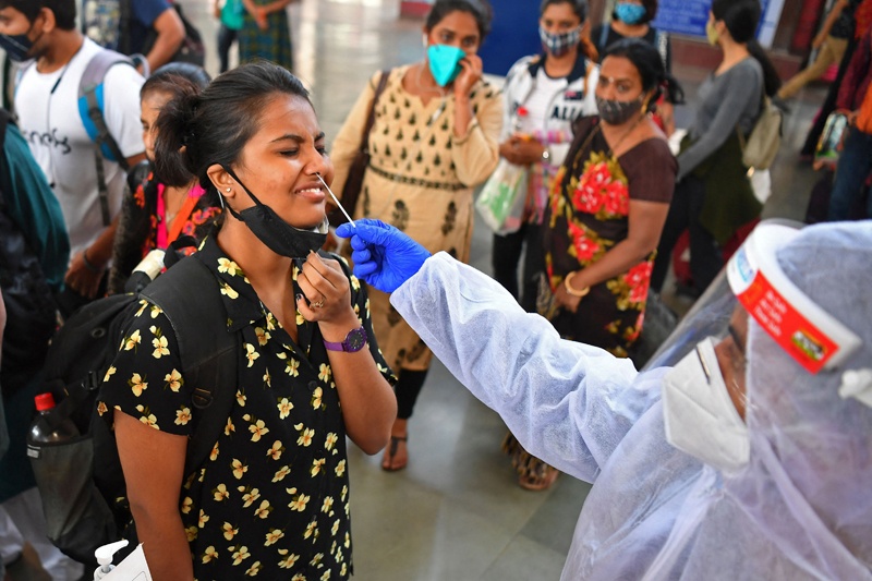 MUMBAI: A health worker wearing protective gear takes a nasal swab sample of arriving passengers for conducting RT-PCR COVID-19 coronavirus tests during a screening at a railway terminus yesterday. - AFP n
