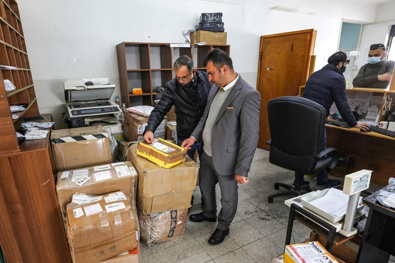 AL-BIREH: Palestinian postal workers examine a mail package at a post office in this city about 15 km north of Jerusalem in the occupied West Bank on Sunday. - AFP n
