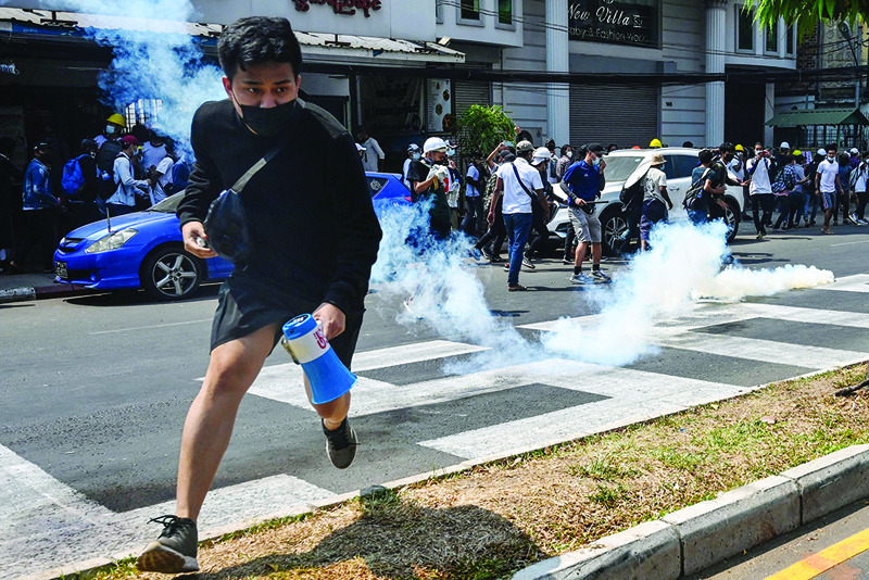 YANGON: Protesters run after police fired tear gas to disperse them during a demonstration against the military coup yesterday. - AFP n