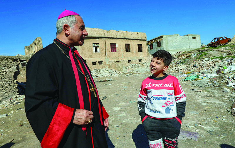 MOSUL: The Chaldean Catholic Archbishop of Mosul Najeeb Michaeer (left) chats with a young resident the old part of the northern city of Mosul, during a tour to follow the progress of restoration works there.-AFP n