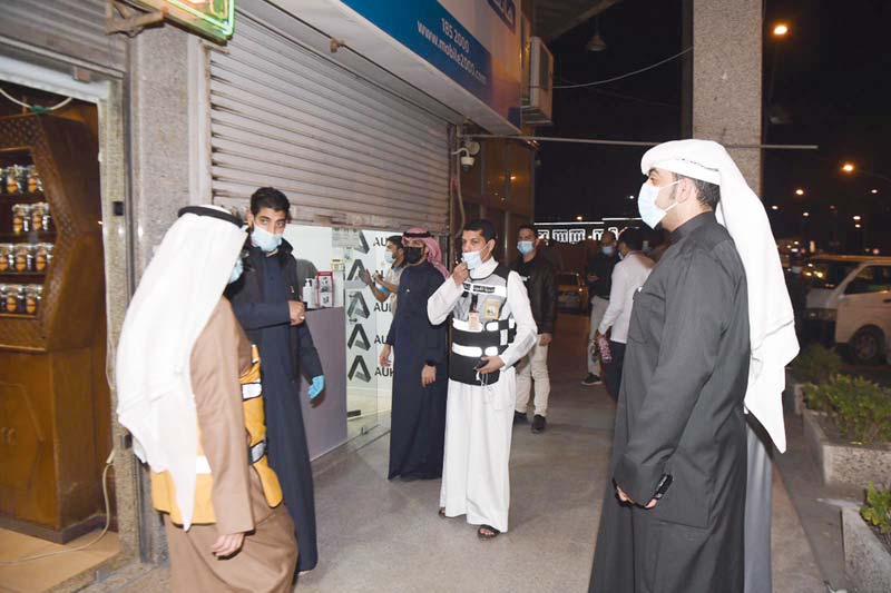 KUWAIT: Kuwait Municipality workers stand outside shops that are closing on 8:00 pm on Monday in compliance with the government's measures to help limit the spread of COVID-19. - Photo by Yasser Al-Zayyatn