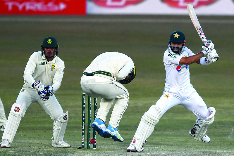 RAWALPINDI: Pakistan’s Mohammad Rizwan (right) plays a shot as South Africa’s wicketkeeper captain Quinton de Kock (left) watches during the third day of the second Test cricket match between Pakistan and South Africa at the Rawalpindi Cricket Stadium in Rawalpindi yesterday. — AFP