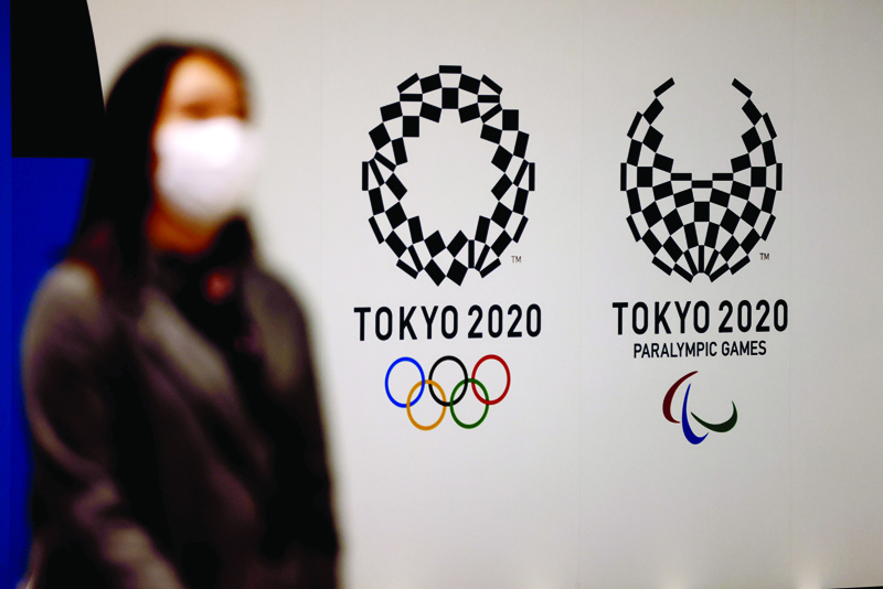 TOKYO: A woman wearing a face mask walks past logos of Tokyo 2020 Olympic and Paralympic Games in Tokyo on Tuesday. - AFPn