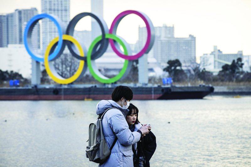 TOKYO: A couple checks pictures after posing in front of the Olympic rings on display at the Odaiba waterfront in Tokyo yesterday. - AFPn