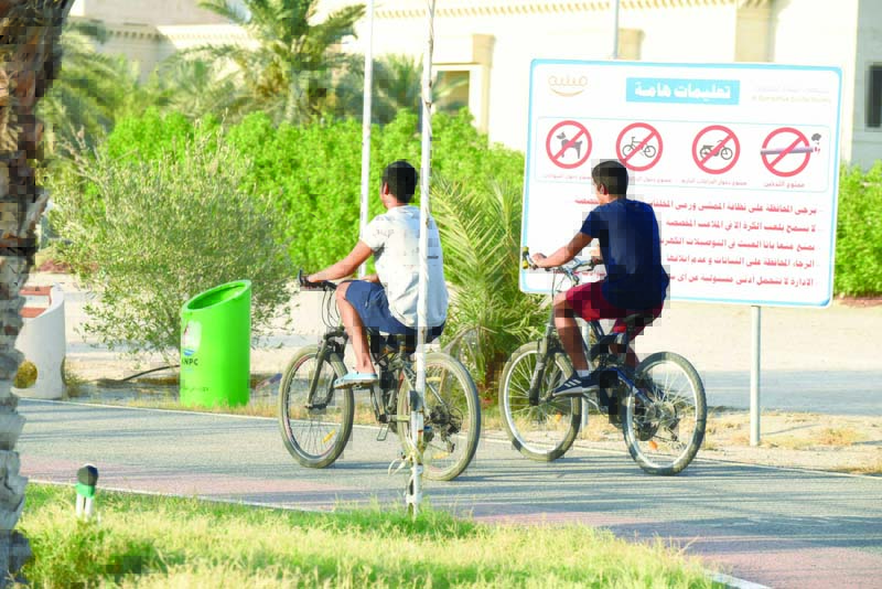KUWAIT: Two kids ride their bicycles in a park before the curfew hours. - Photo by Fouad Al-Shaikhn