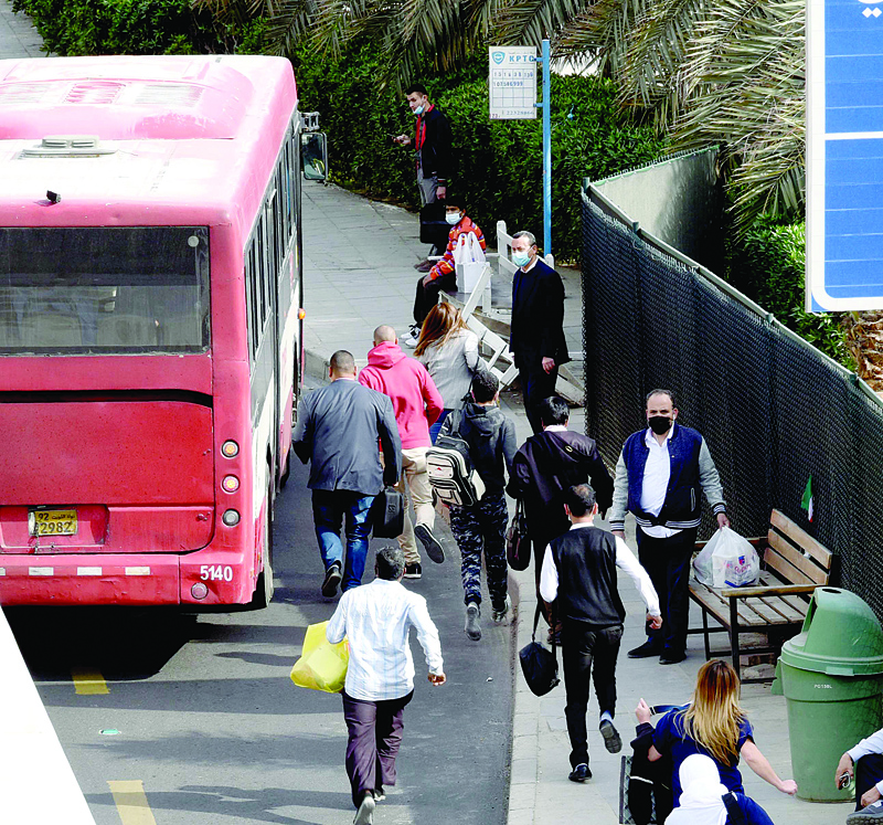 KUWAIT: People race to catch the bus at a bus stop in Kuwait City in this file photo. Finding public transportation remains a daily struggle for people who try to reach home in time before the curfew starts at 5:00 pm. - Photo by Fouad Al-Shaikhn