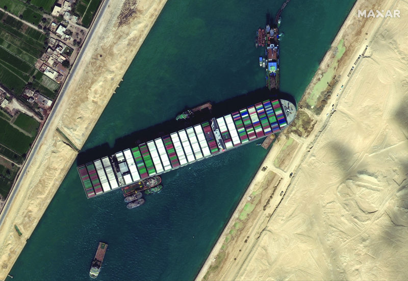 This satellite imagery released by Maxar Technologies shows tug boats and dredgers on Saturday  attempting to free the Taiwan-operated MV Ever Given lodged sideways and impeding all traffic across Egypt's Suez Canal. - AFPn