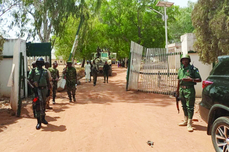 Nigerian soldiers and police officers stand at the entrance of the Federal College of Forestry Mechanisation in Mando, Kaduna state on Friday after a kidnap gang stormed the school, shooting indiscriminately before taking at least 30 students.-AFPn