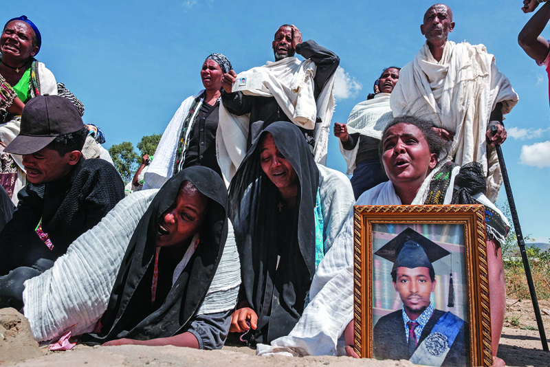 People react as they stand next to a mass grave containing the bodies of 81 victims of Eritrean and Ethiopian forces, killed during violence of the previous months, in the city of Wukro, north of Mekele. - AFPn