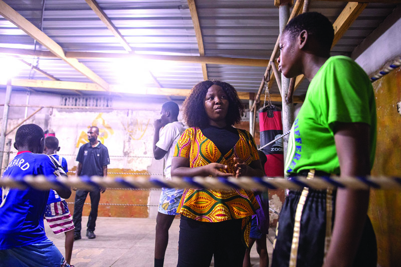 ACCRA: Sarah Lotus Asare (second left), a volunteer who works with disadvantaged teenage girls, interacts with a girl in a boxing gym in James Town, Accra, Ghana.-AFPn