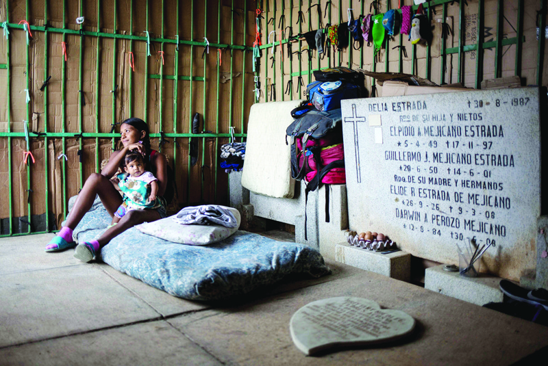 CARACAS: A young woman and a baby rest at a makeshift refuge at the southern general cemetery in Caracas.-AFP n