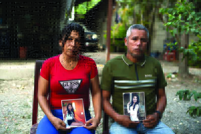 LA MISION, Venezuela: Mileidys Torrealba (left), 39, and Eduard Jose Falcon, 45, pose with portraits of their 20-year-old daughter Eduarlis Falcon, who was murdered alongside another girl, at their house in La Mision, Portuguesa state, Venezuela. - AFPn