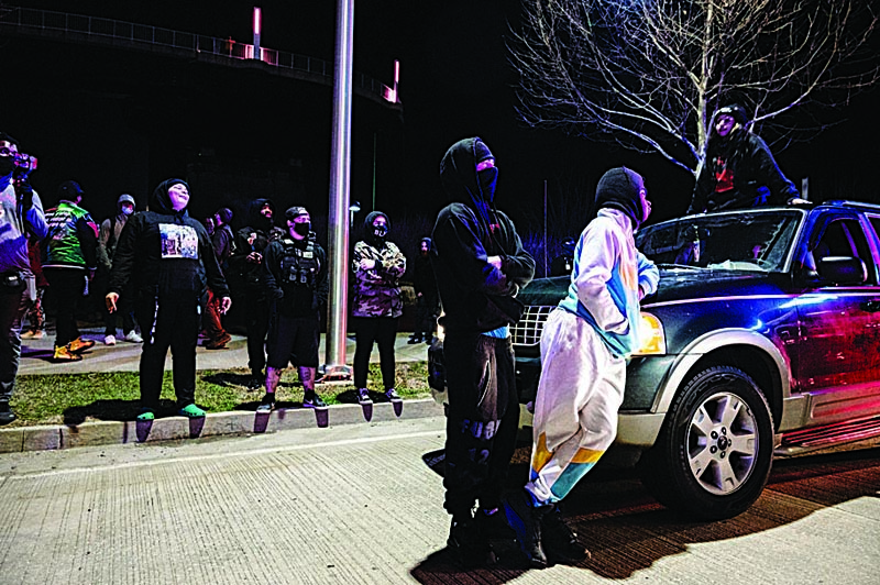 LOUISVILLE, KY: A group of protesters are illuminated by emergency lights from Louisville Metro Police Department vehicles after the Breonna Taylor memorial events on Saturday in Louisville, Kentucky. - AFPn