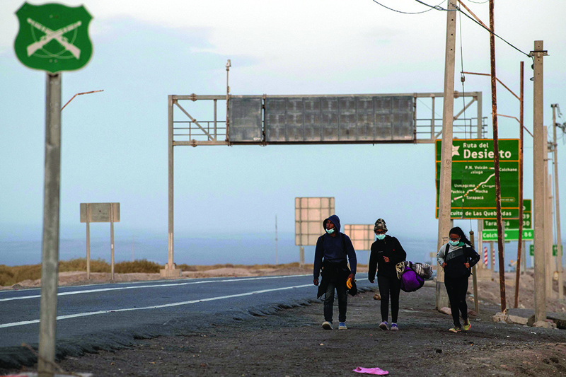 COLCHANE, Chile: Venezuelan migrants Reinaldo (left), 26, Anyier (center), 40, and her daughter Danyierly, 14, walk along the highway on their way to Iquique, after crossing from Bolivia, in Colchane, Chile.-AFP n