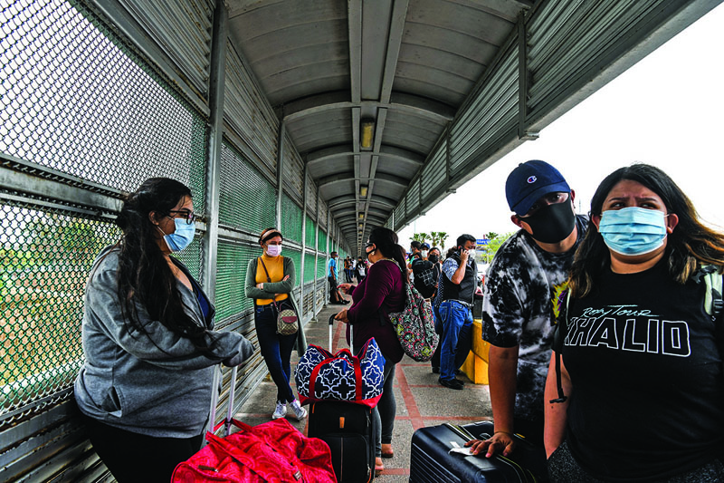 Migrants mostly from Central America wait in line to cross the border at the Gateway International Bridge into the US from Matamoros, Mexico to Brownsville, Texas.-AFPnn