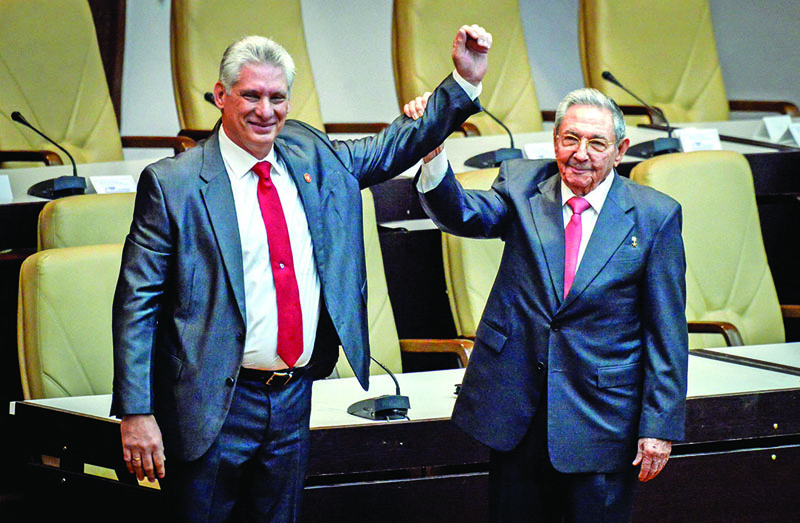 HAVANA: In this file photo taken on April 19, 2018 outgoing Cuban President Raul Castro (right) raises the arm of Cuba's new President Miguel Diaz-Canel after he was formally named by the National Assembly, in Havana. - AFPn