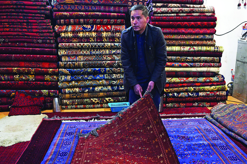 In this picture Chari Allahqul, a rug hunter displays a rug during an interview with AFP inside his shop at Chicken Street in Kabul.-AFP photosn