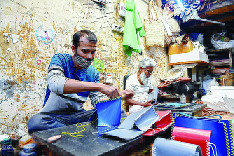 Artisans Rahul Dattatrey Gorey (left) and Kalamuddeen Ansari stitch new recycled rubber bags. n