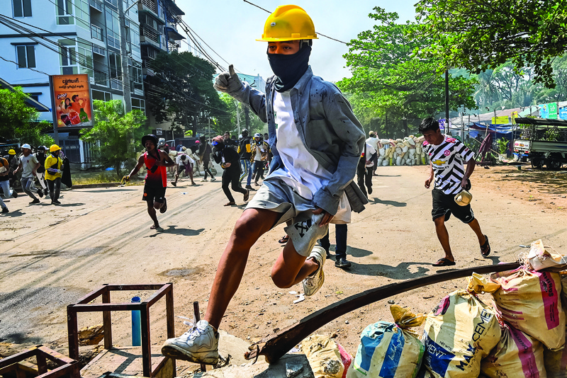 YANGON: A protester jumps over a makeshift barricade during a crackdown by security forces on a demonstration against the military coup in Yangon's Thaketa township yesterday.—AFPn
