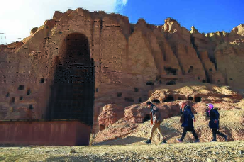 Hazara people walk at the site of the giant Buddha statues, which were destroyed by the Taleban in 2001, in Bamiyan province.-AFPn