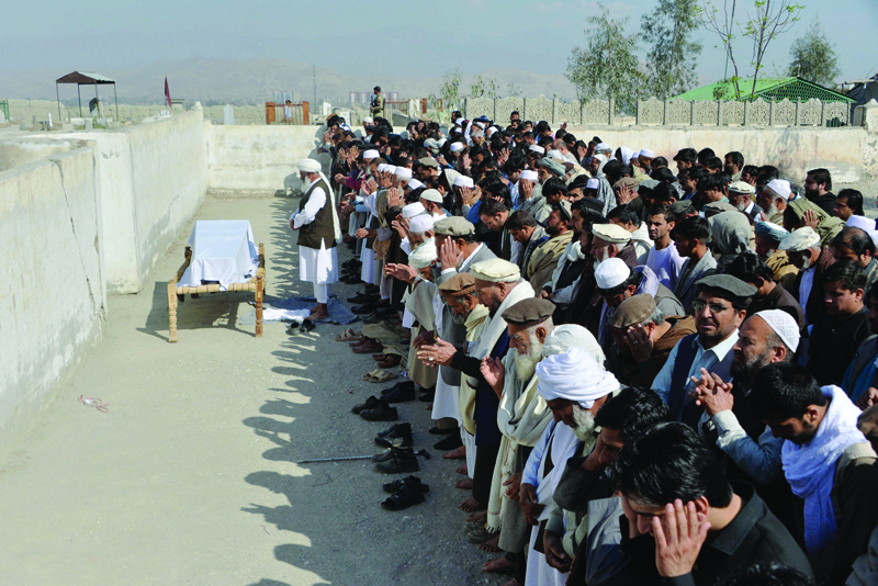 JALALABAD, Afghanistan: Relatives and mourners perform funeral prayers over the coffin of one of the three female media workers shot to death in two separate attacks, in Jalalabad yesterday.-AFP n