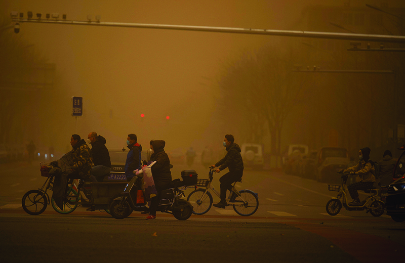 BEIJING: People cross a street during a sandstorm in Beijing yesterday.-AFP n