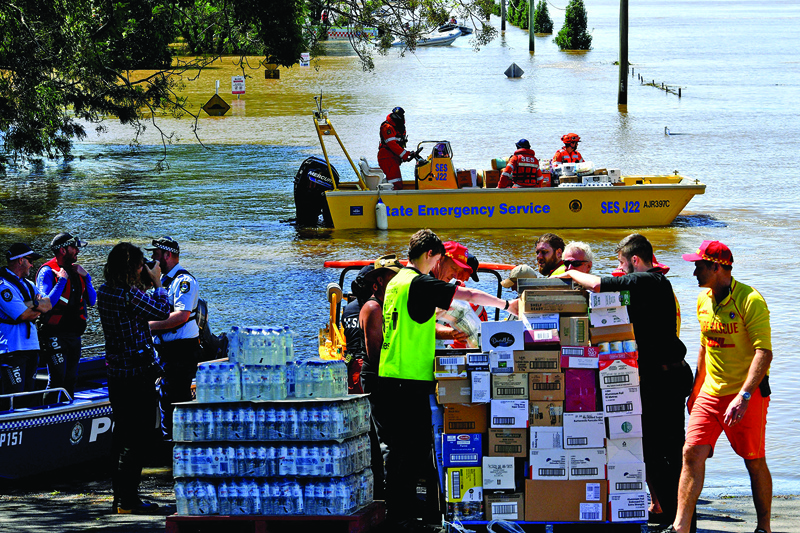 SYDNEY: Members of the State Emergency Service transport relief goods during rescue operations at a flooded residential area in the Windsor suburb of northwestern Sydney yesterday after torrential downpours have lashed Australia's southeast for days. - AFPnn