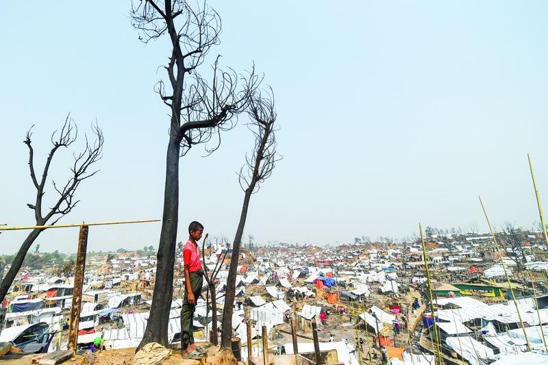 A Rohingya refugee child stand at his burnt home days after a fire at a refugee camp in Ukhia, in the southeastern Cox's Bazar district yesterday.-AFPn