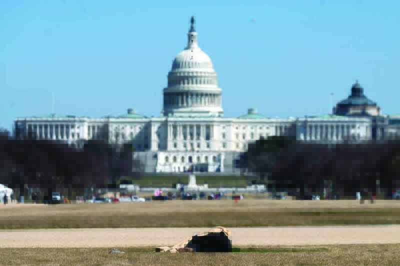 WASHINGTON, DC: A homeless man sleeps on the National Mall near the US Capitol in Washington, DC on Monday. The American Rescue Plan, the bill, which was approved by the Senate last week and is set for a vote in the House today.-AFPn