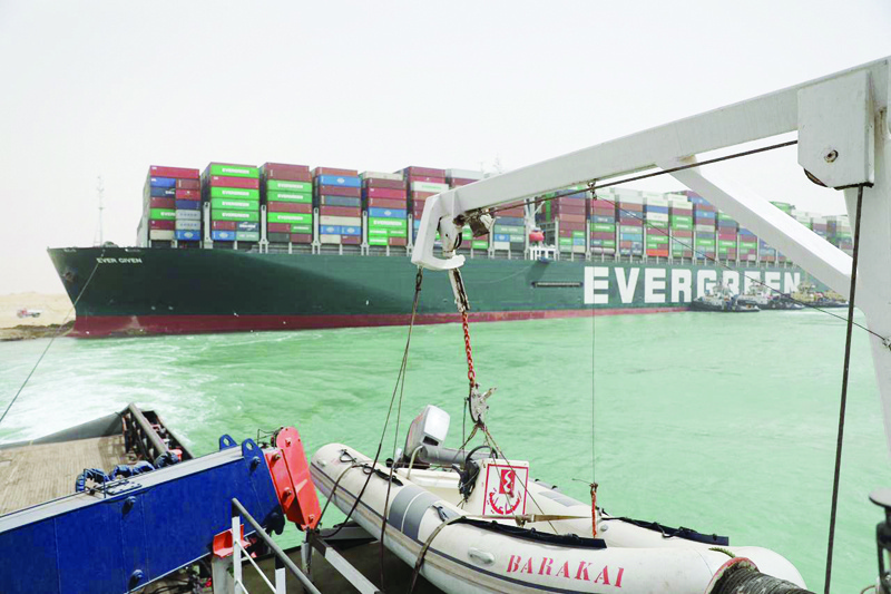 A handout picture released by the Suez Canal Authority yesterday shows Egyptian tug boats trying to free Taiwan-owned cargo MV Ever Given (Evergreen), a 400-metre- (1,300-foot-)long and 59-metre wide vessel, lodged sideways and impeding all traffic across the waterway of Egypt's Suez Canal. - AFPn