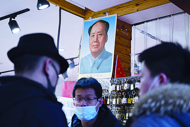 BEIJING: Men chat below a portrait of late communist leader Mao Zedong at a store in Beijing yesterday ahead of the upcoming annual meeting of the National People's Congress. More than 200 billionaires were created in China last year as booming stock markets and a flood of new listings offset the ravages of the virus pandemic, according to a global tally released yesterday. -- AFPnn
