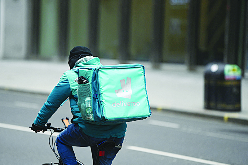 LONDON: A Deliveroo rider cycles through central London. Deliveroo shares slumped 15 percent at the start of its entry in the London stock market yesterday as the app-driven meals delivery group faces criticism over its treatment of riders. - AFPn