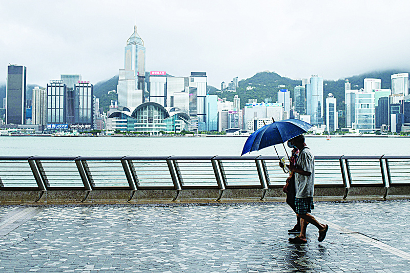 HONG KONG: This file photo shows two pedestrians using umbrellas on a promenade that runs along Victoria Harbour in Hong Kong. Hong Kong has been removed from an annual index of the world's freest economies yesterday because The Heritage Foundation, the conservative US think-tank that compiles the league table, said the city was now directly controlled by Beijing. - AFPn