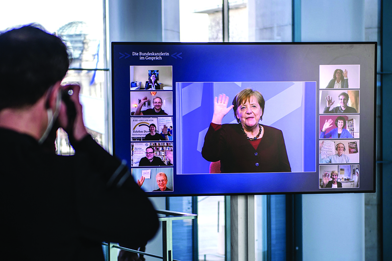 BERLIN: German Chancellor Angela Merkel waves as she can be seen on a screen inside the Chancellery during a video conference of the digital dialog series 'The Federal Chancellor in Conversation' at the Chancellery in Berlin. - AFPn