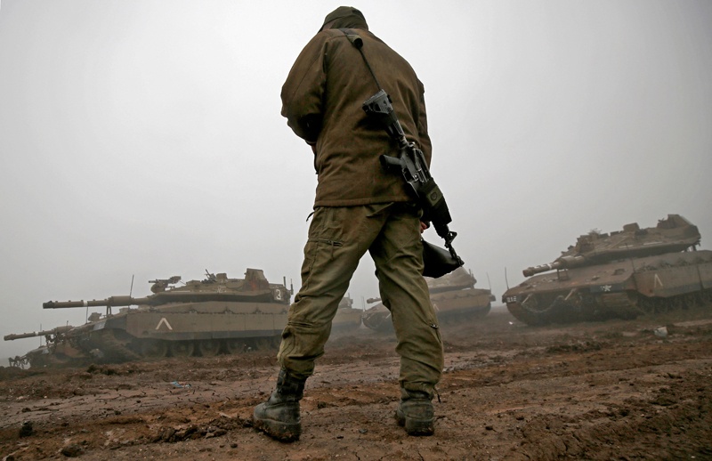An Israeli soldier walks towards parked Merkava Mark IV battle tanks near Moshav Alonei HaBashan in the Israeli-annexed Golan Heights during heavy fog on March 1, 2021. - AFP