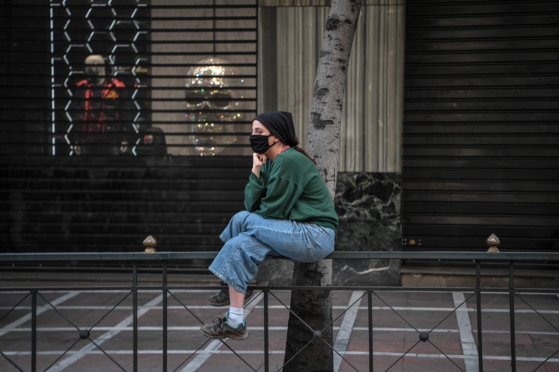 ATHENS: A woman sits in front of closed stores in central Athens yesterday as Greece is under lockdown due to the COVID-19 pandemic. – AFP n