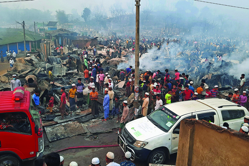 UKHIA, Bangladesh: Onlookers gather at a Rohingya refugee camp yesterday, which was hit by a huge blaze. - AFP n