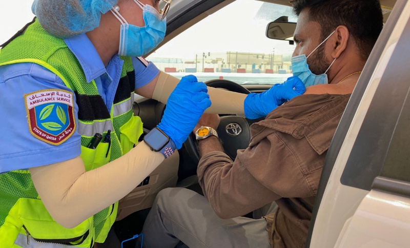 AL WAKRAH, Qatar: A health worker inoculates a man against the coronavirus at a drive-through vaccination center yesterday. - AFP  n