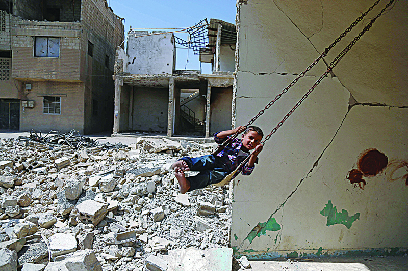 A Syrian boy plays on a swing in a destroyed building in the rebel-held town of Douma, on the eastern outskirts of Damascus. A decade since Arab Spring protests rocked the Middle East and North Africa, many of its youth are in need and at risk, says the UN children's agency's regional director. - AFPn
